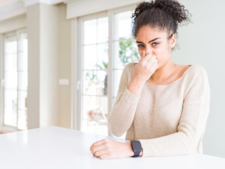 a woman pinching her nose because of odor in her house.